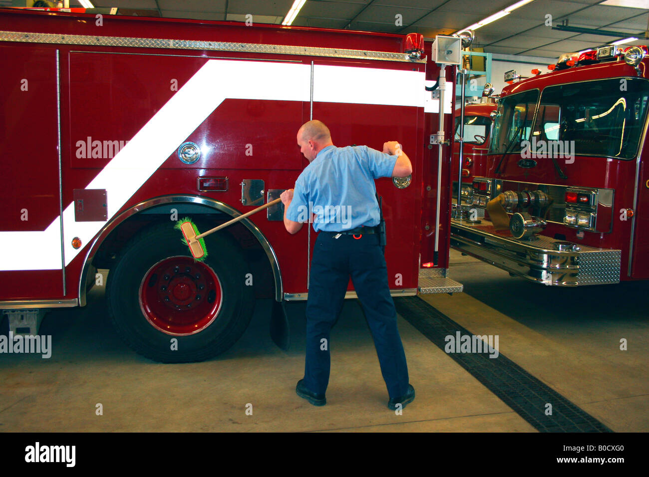 Firefighter cleaning tires on Fire Engine Stock Photo