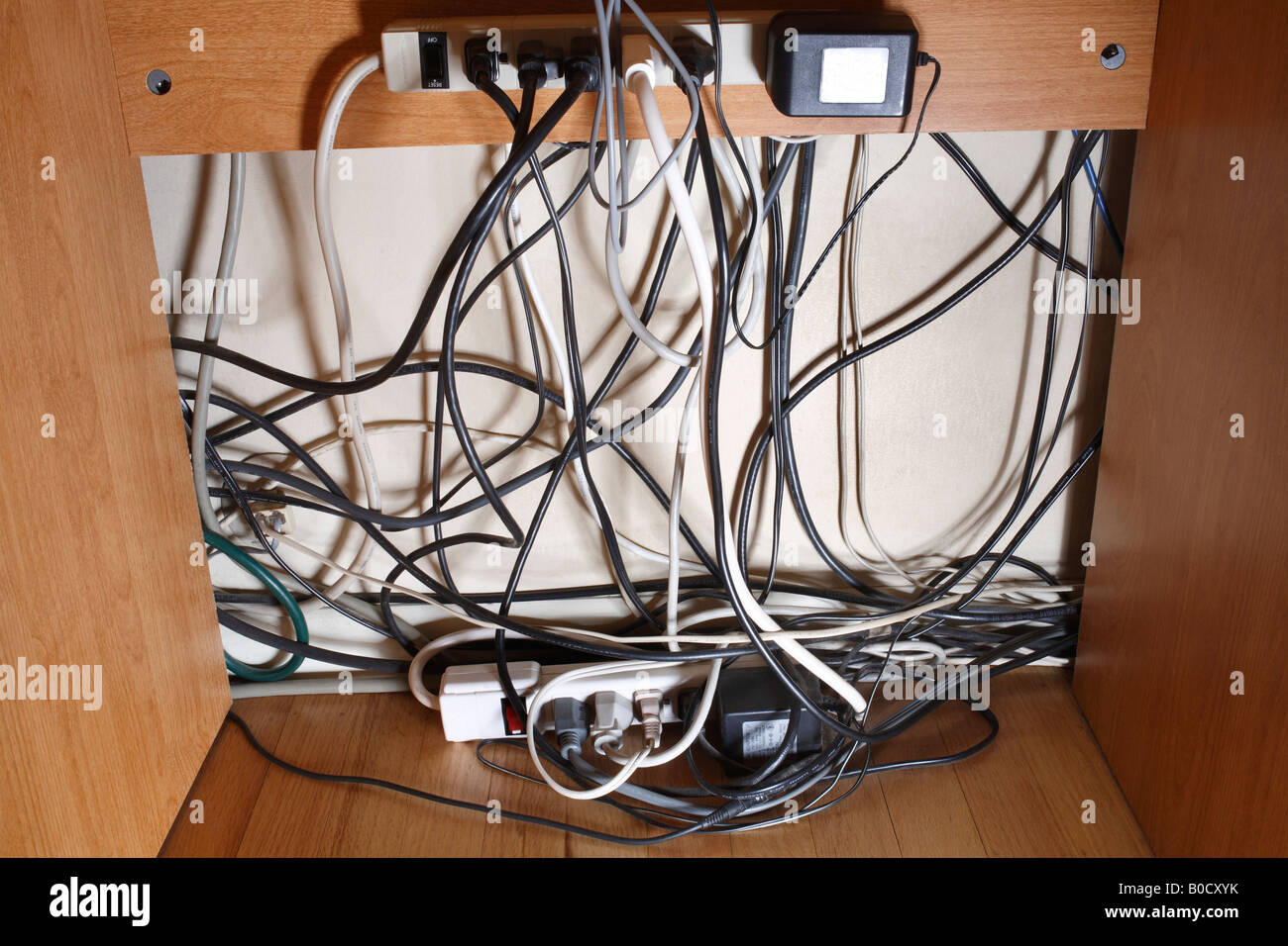 Power strips power cords computer cables under desk Stock Photo