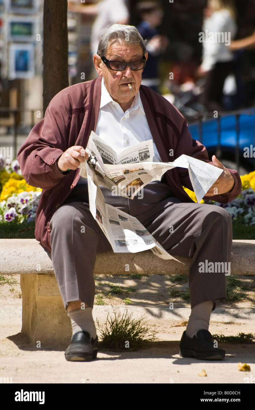 old man reading a newspaper on a park bench, Valencia, Spain, april 2008 Stock Photo