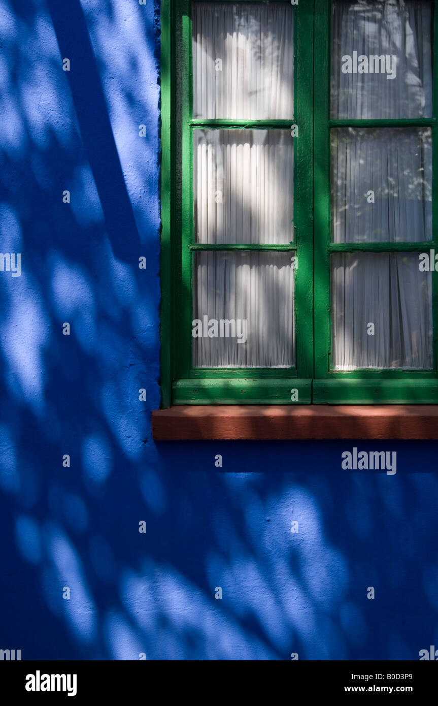 Dappled shadows on a window at Frida Kahlo's house known as the Blue House. Bright blue with contrasting green colour Stock Photo