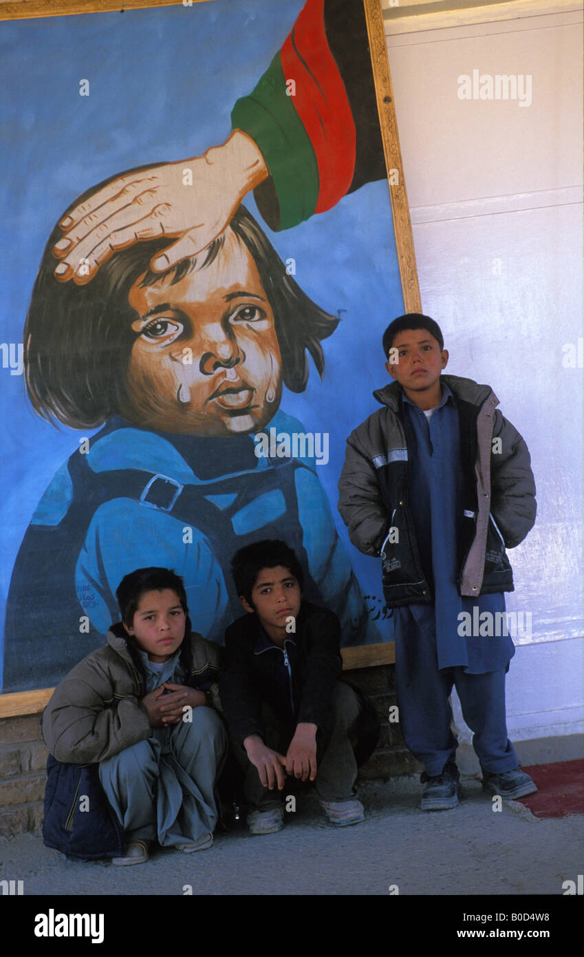 Kabul portrait of a boys in front of a painting which claims the government is taking care of the Afghan children Stock Photo