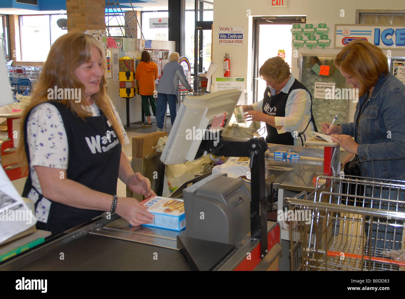 A cashier scans items for a customer at the checkout of a grocery store. Stock Photo