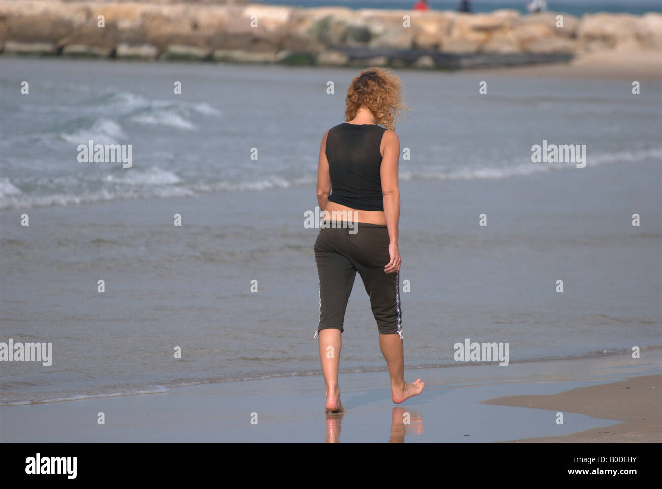 Israel Tel Aviv beach front lone woman strolling on the water front Stock Photo