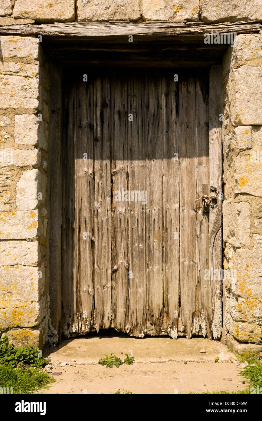 Rustic, weathered wooden door in stone wall Stock Photo - Alamy
