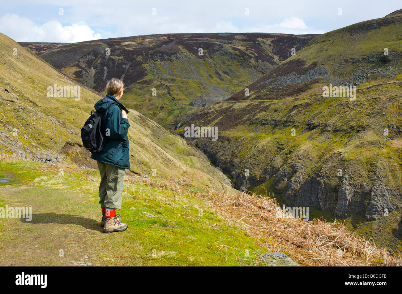 Female walker looking up Swinner Gill towards lead mines, near Muker, Upper Swaledale, Yorkshire Dales National Park, England UK Stock Photo