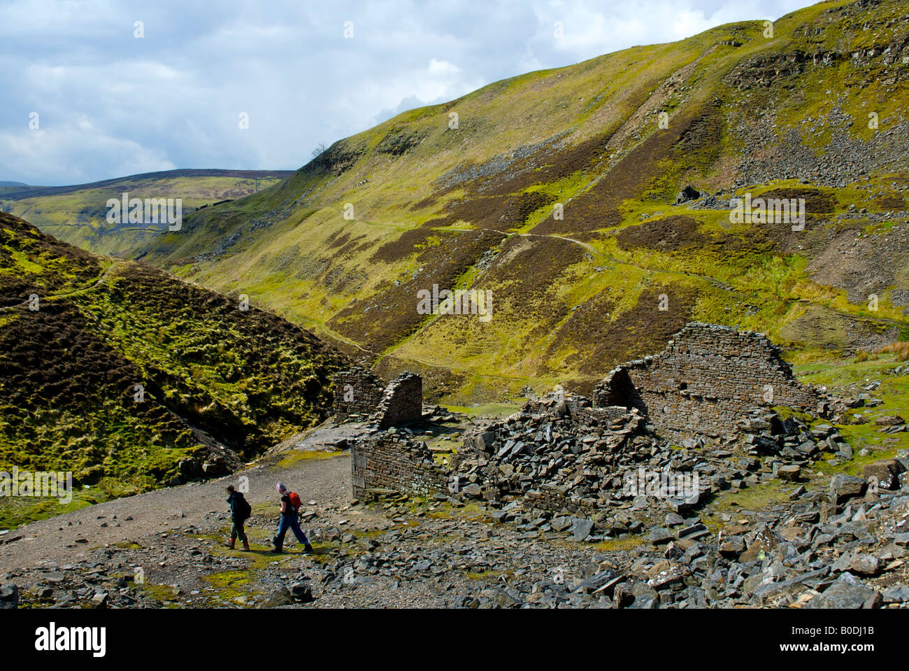 Two walkers at remains of lead mines, Swinner Gill, near Muker, Upper Swaledale, Yorkshire Dales National Park, England UK Stock Photo