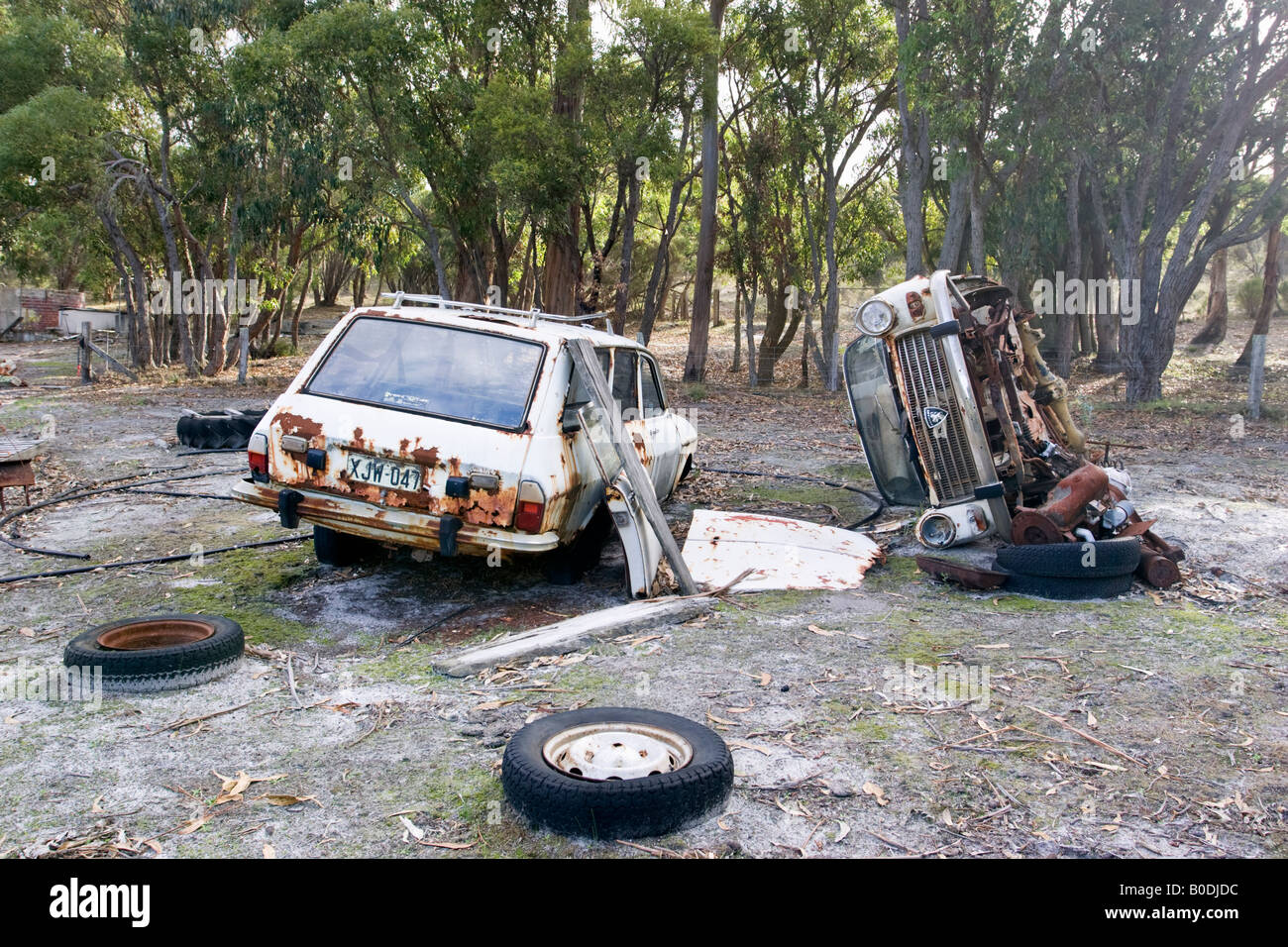 Two rusting, abandoned cars in the corner of a field Stock Photo
