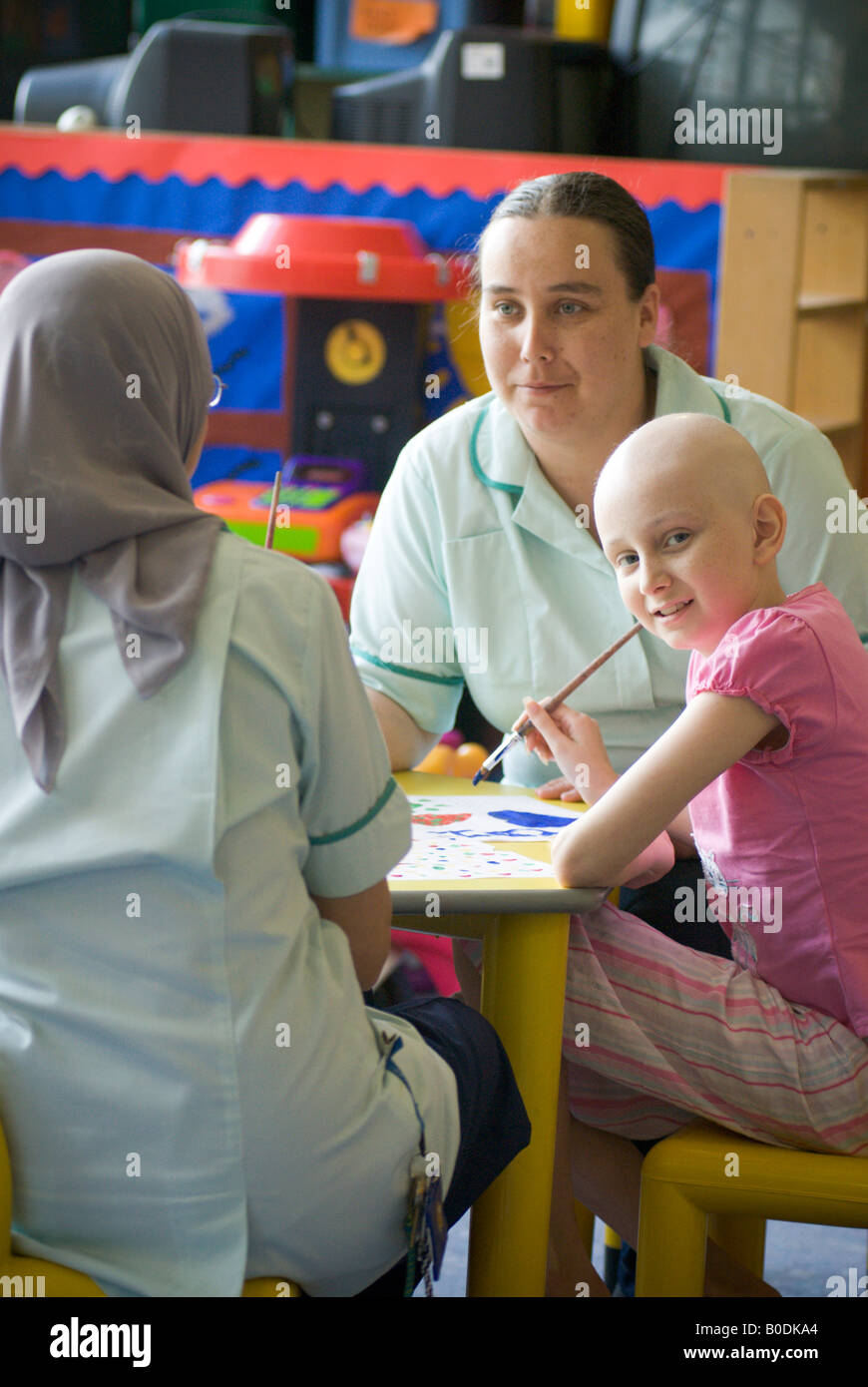 A young girl sits painting with her care workers in hospital children