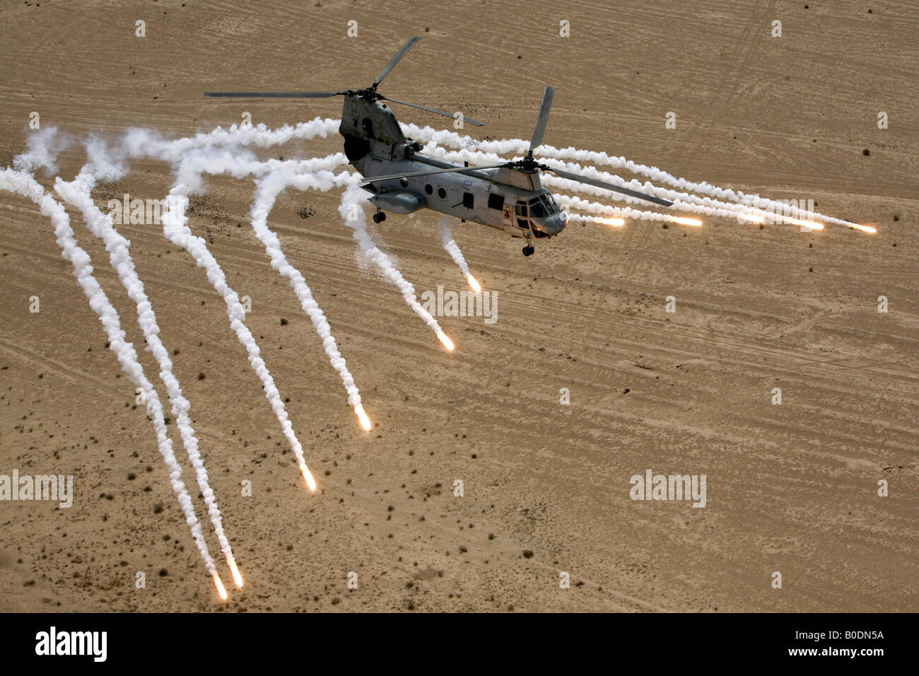 U S Marine Corps CH 46 Sea Knight helicopter launches flares as it flies over the desert near Al Taqqadum Iraq Stock Photo