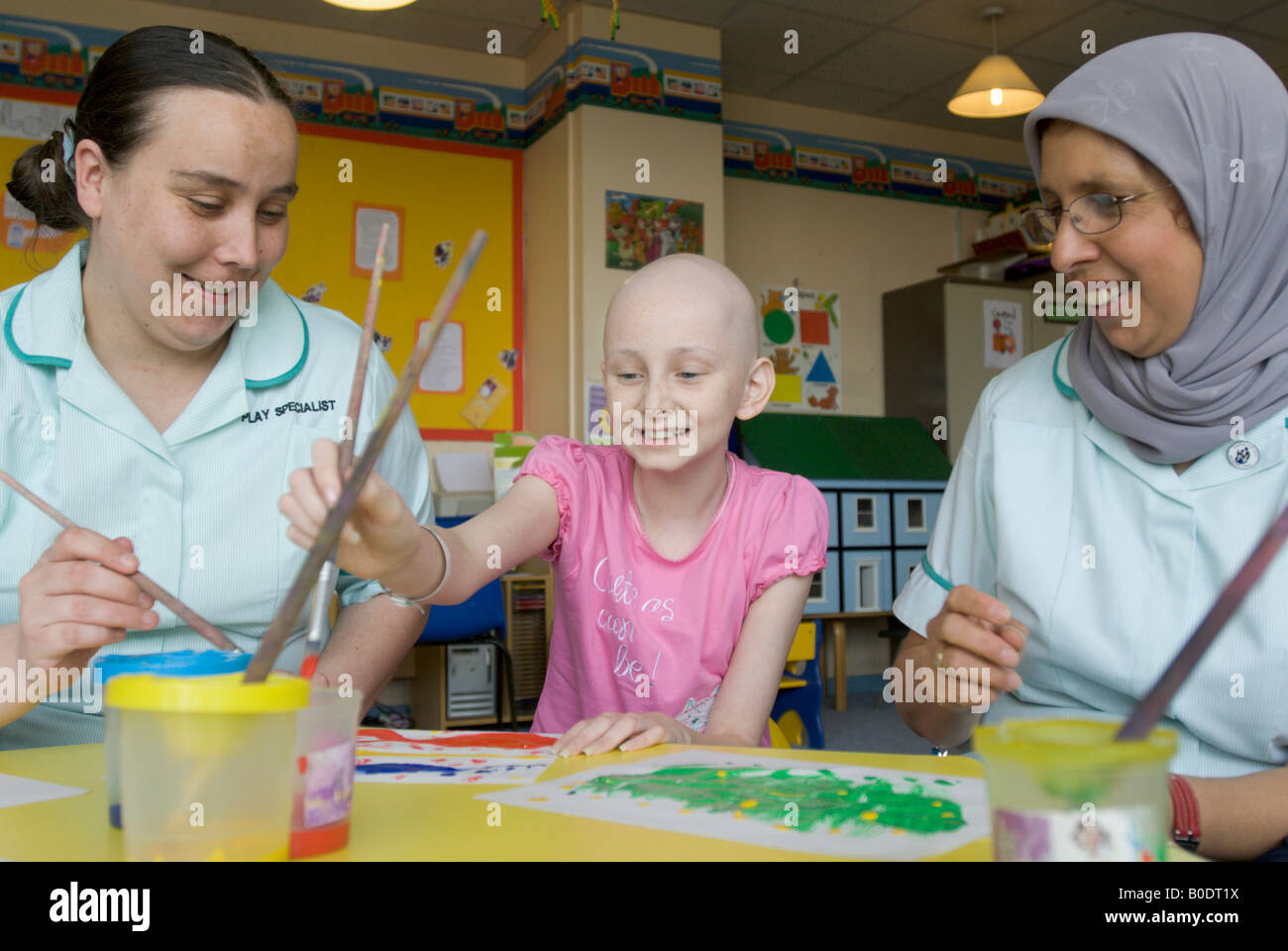 A young girl paints with her care workers in a hospital children ward