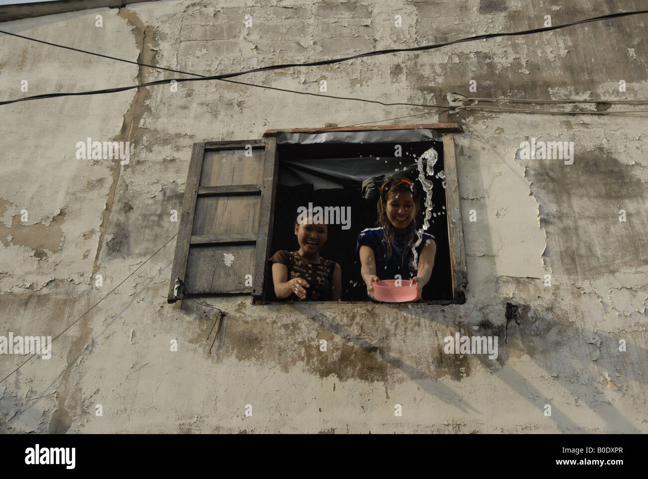 two girls enjoy throwing water to people from their room, songkran festival, thailand Stock Photo