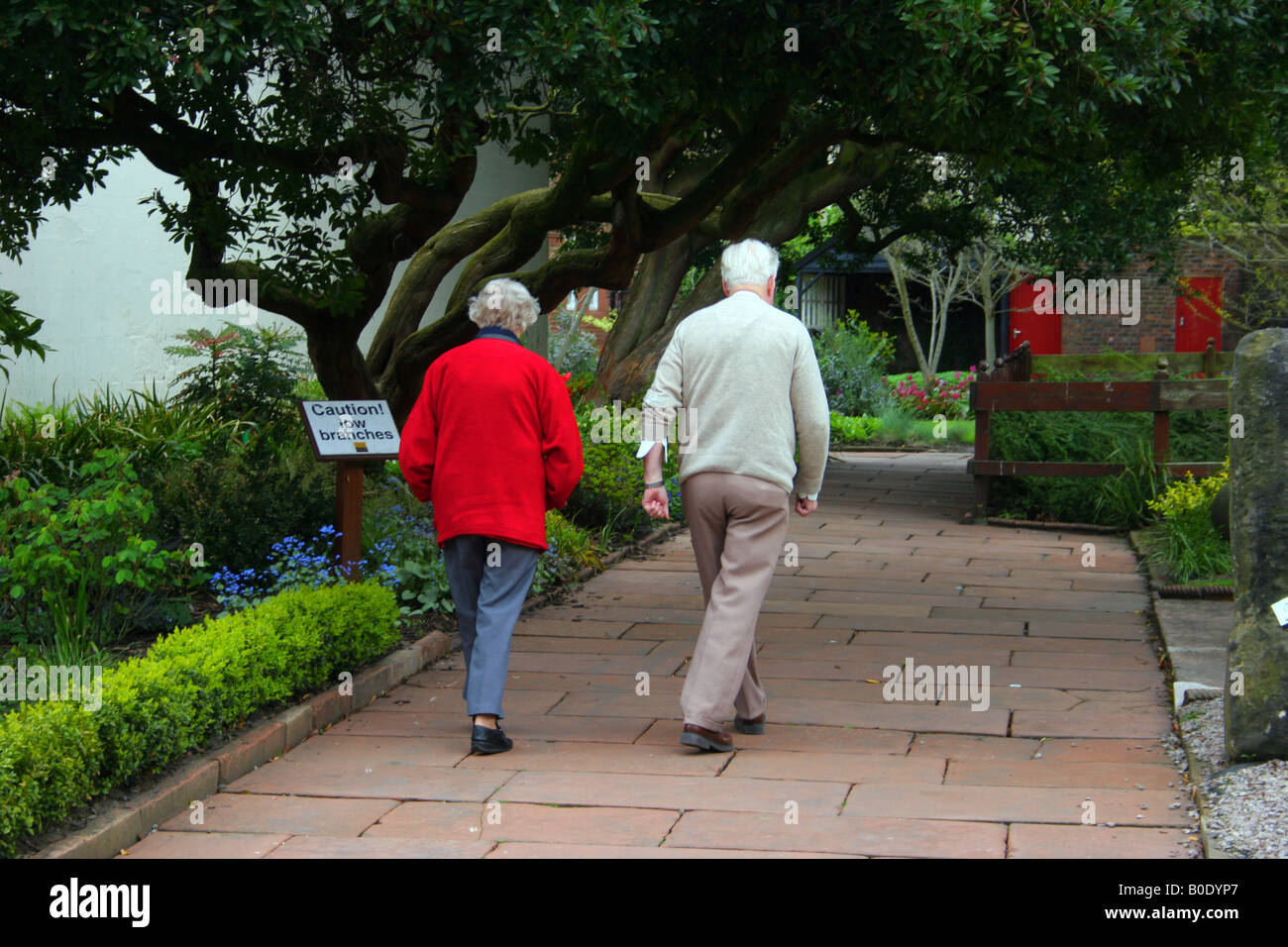 old age couple walking through the tullie house museum grounds Stock Photo