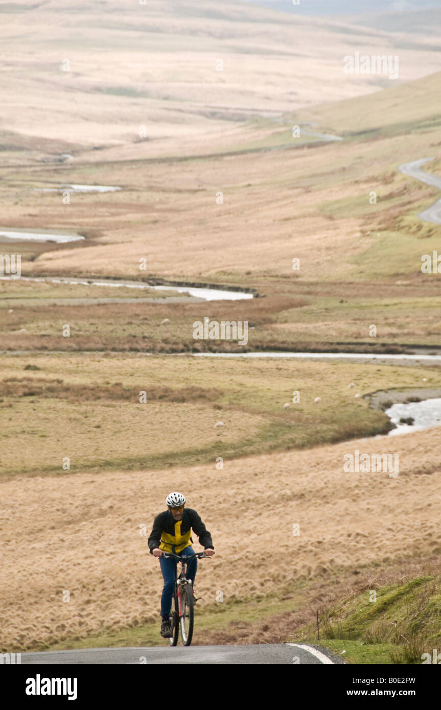 A Middle aged man on bicycle cycling uphill in the Elan Valley Powys mid wales UK Stock Photo