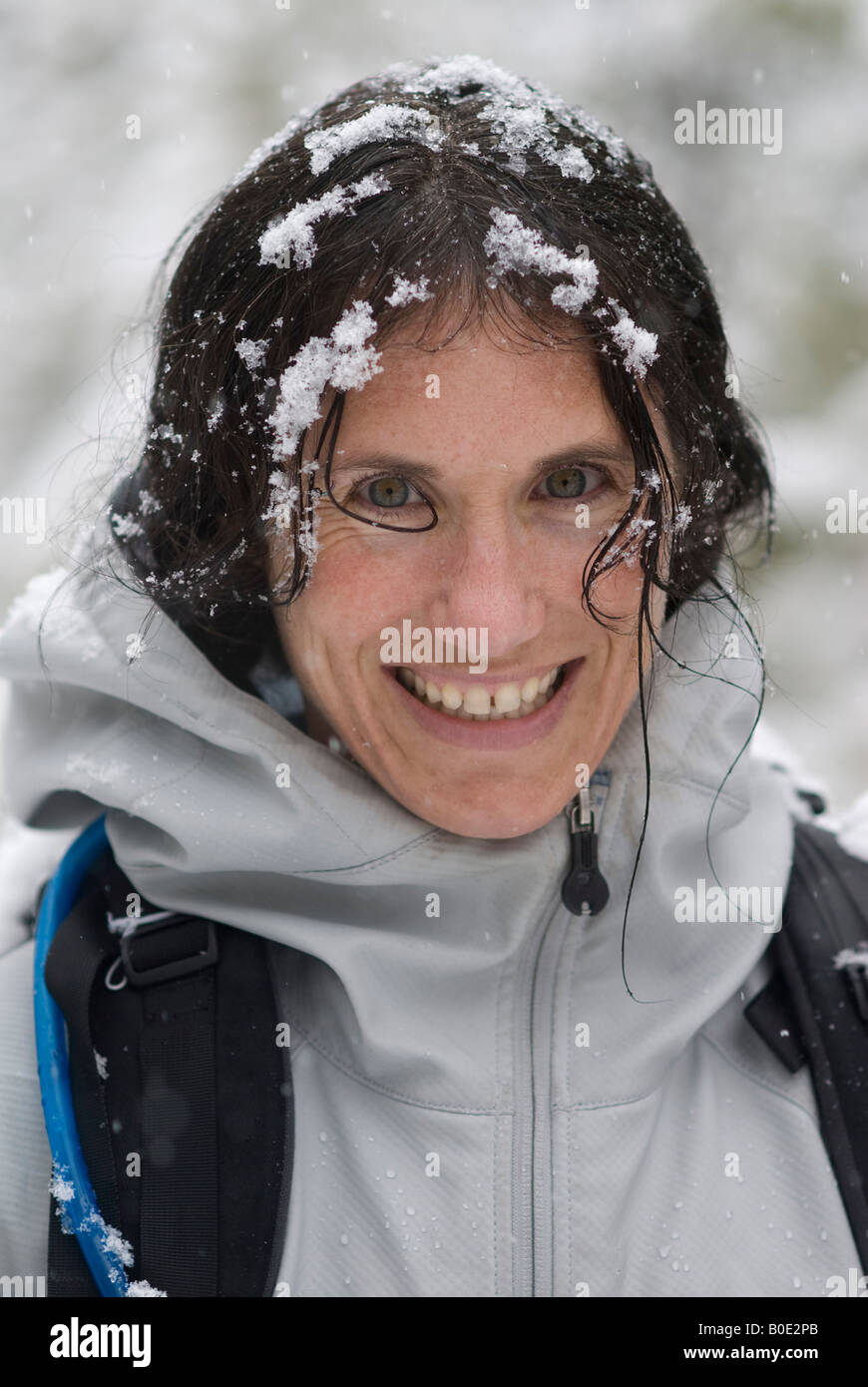 Winter outdoor portrait of a happy woman wearing a backpack in a snowstorm Stock Photo