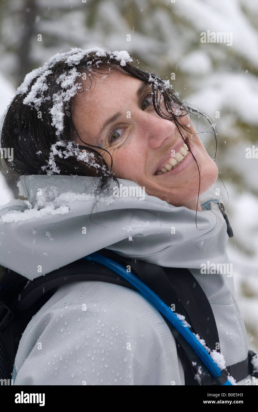 Winter outdoor portrait of a happy woman wearing a backpack in a snowstorm Stock Photo