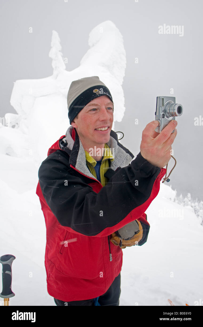skier taking a photo with his Canon PowerShot digital camera, Selkirk Mountains, British Columbia, Canada Stock Photo