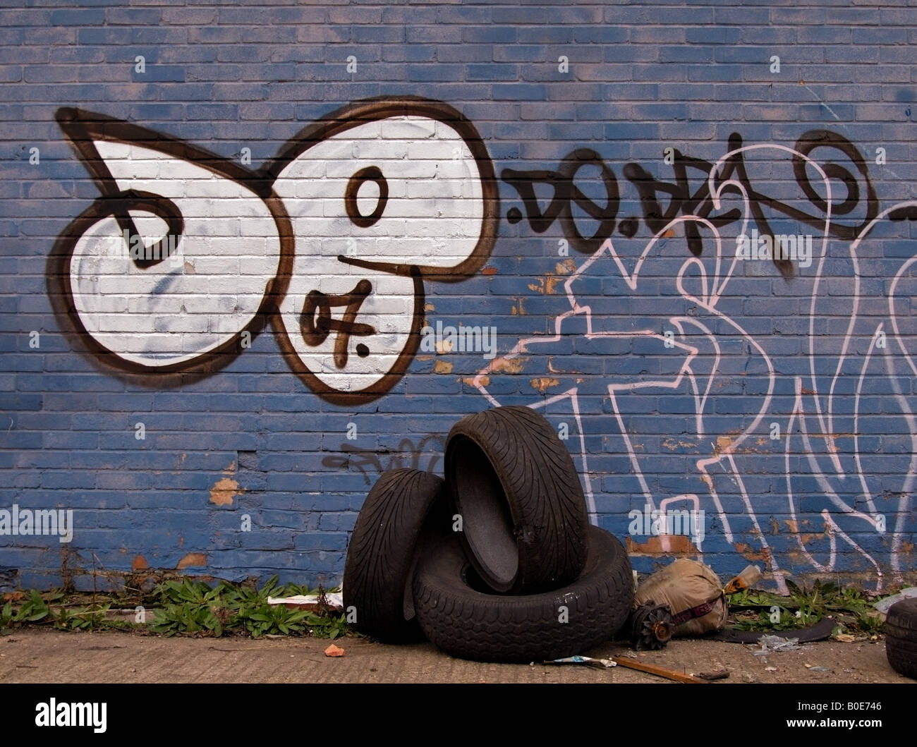 Blue Graffiti Wall and Discarded Tyres Stock Photo
