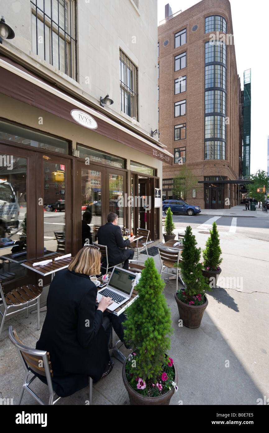 Woman working on a laptop computer outside a restaurant on Greenwich Street, Tribeca, Manhattan, New York City Stock Photo