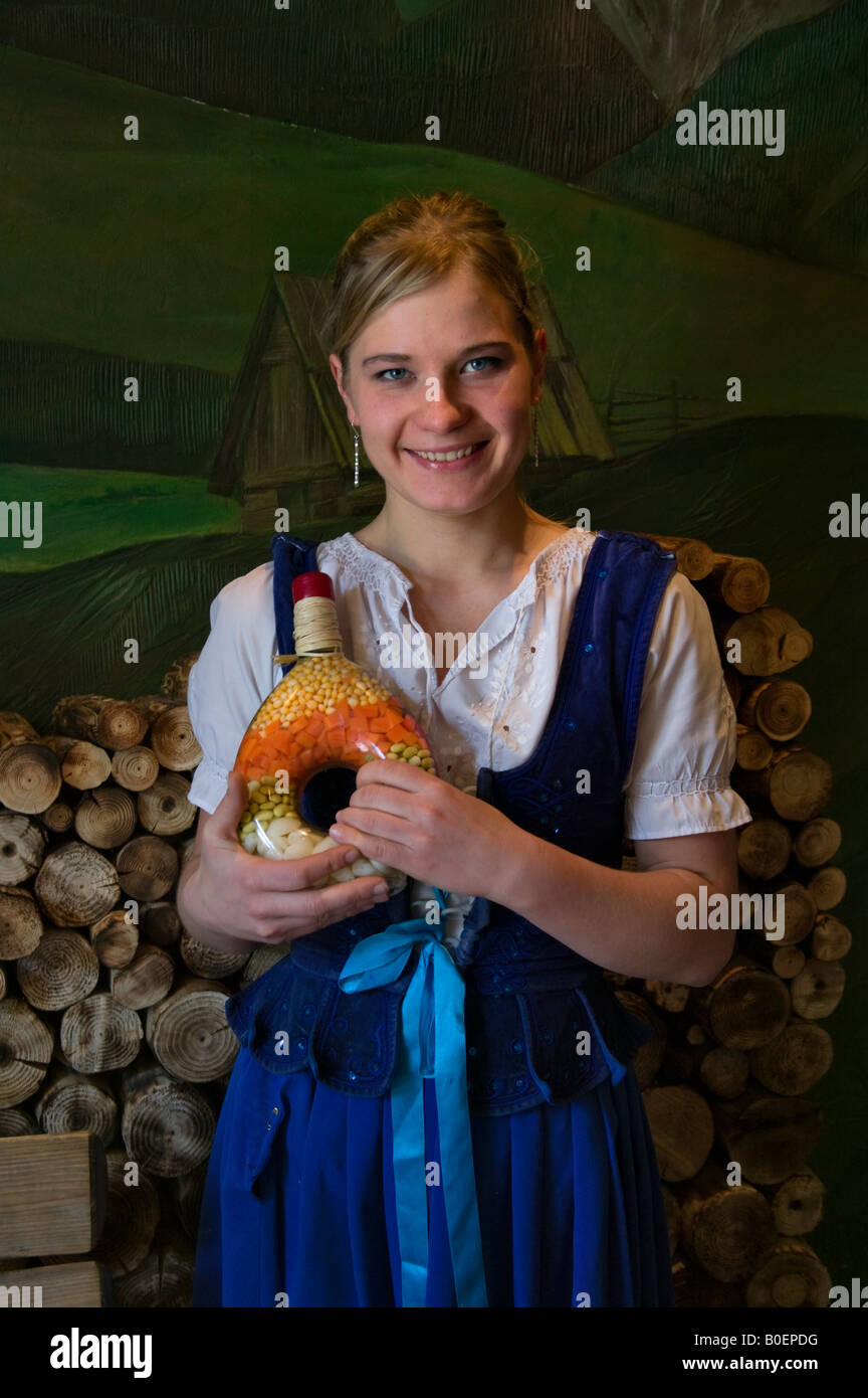 Girl in traditional costume holding bottle of garlic and spices in a