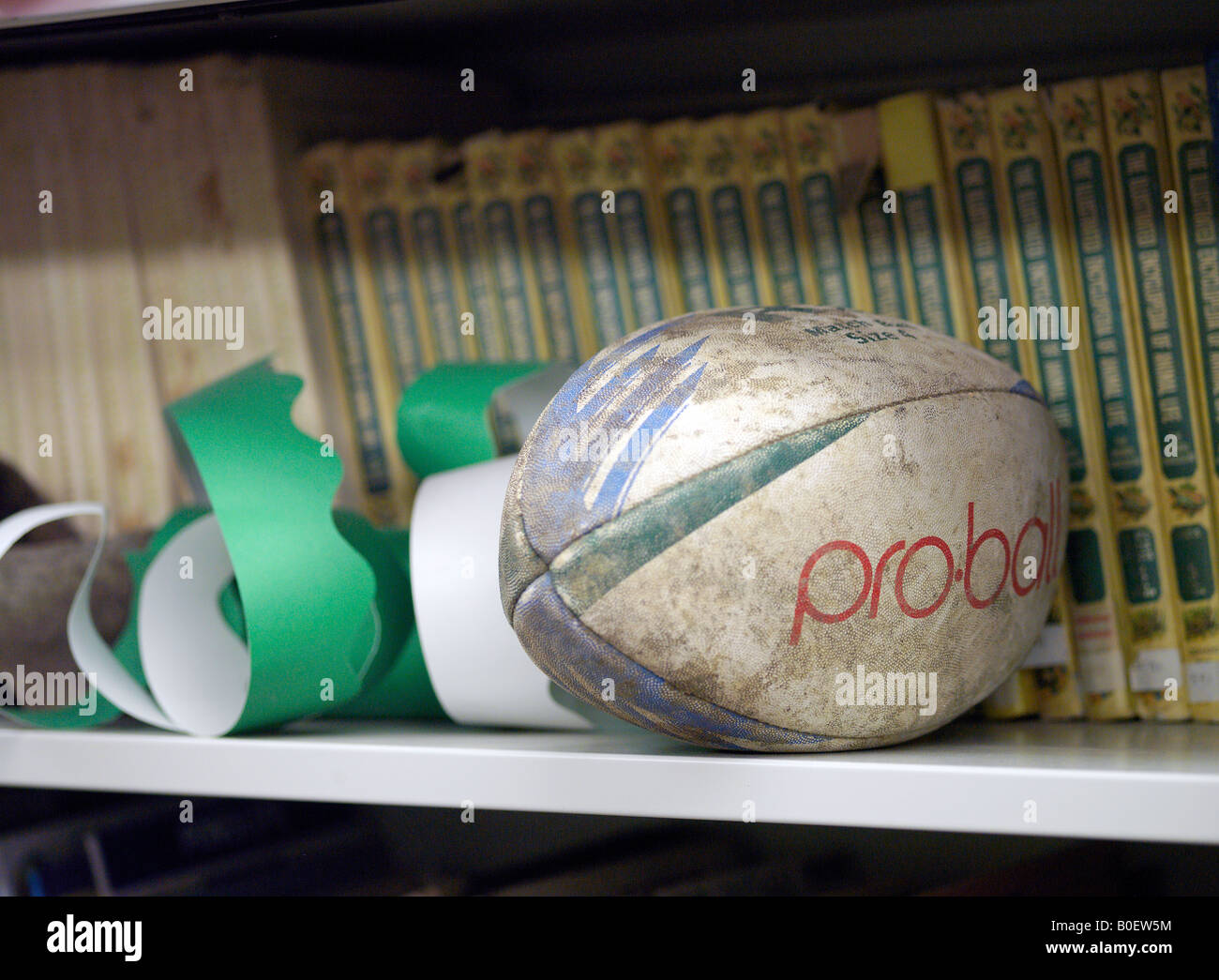 rugby ball on shelf with party hats & schoolbooks Stock Photo
