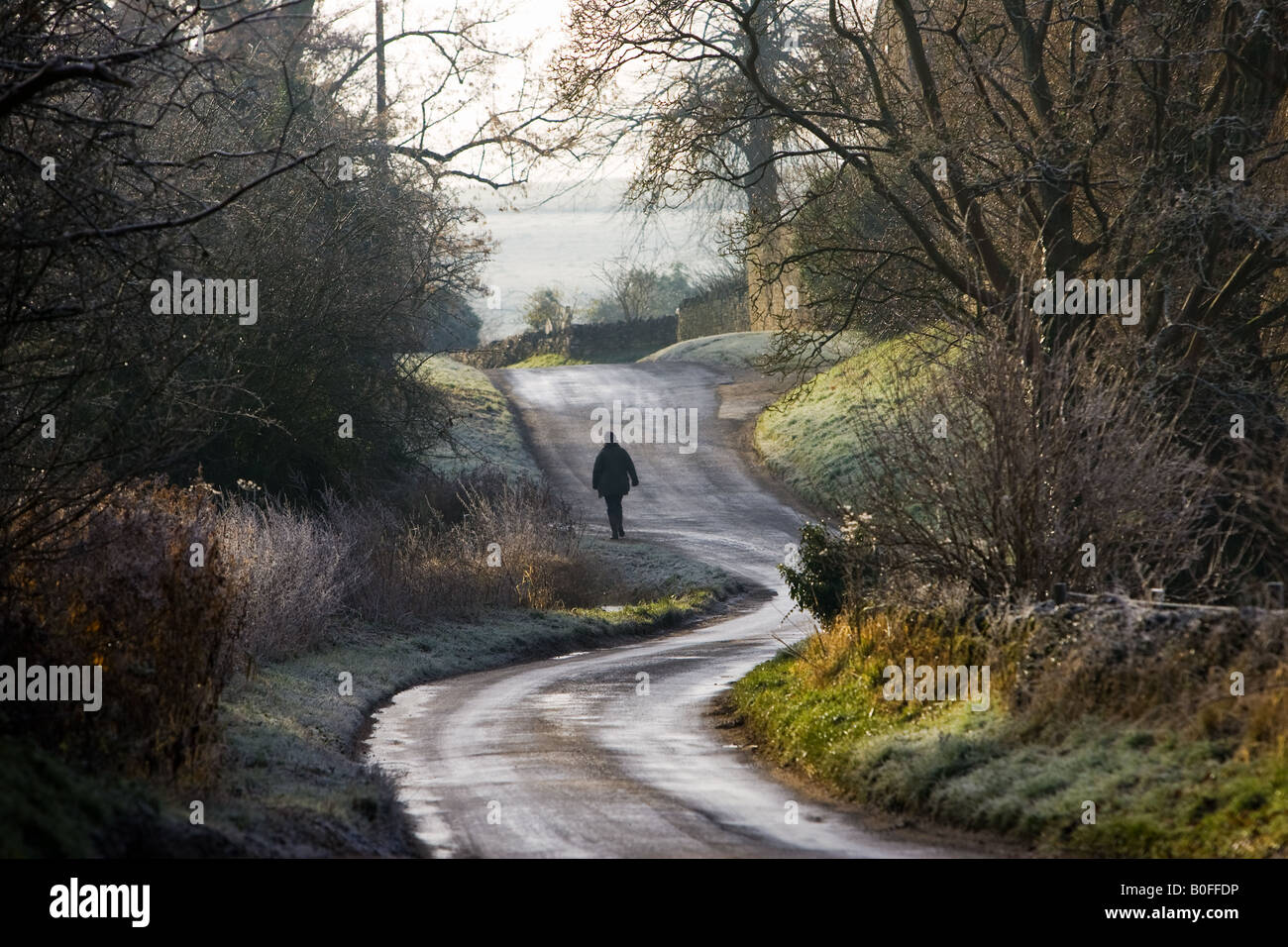 Women walks in a frost covered country lane Swinbrook The Cotswolds