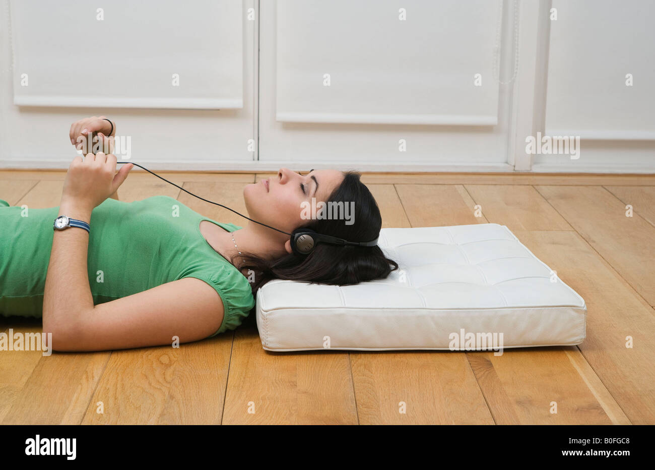 Woman lying on floor listening to music Stock Photo - Alamy