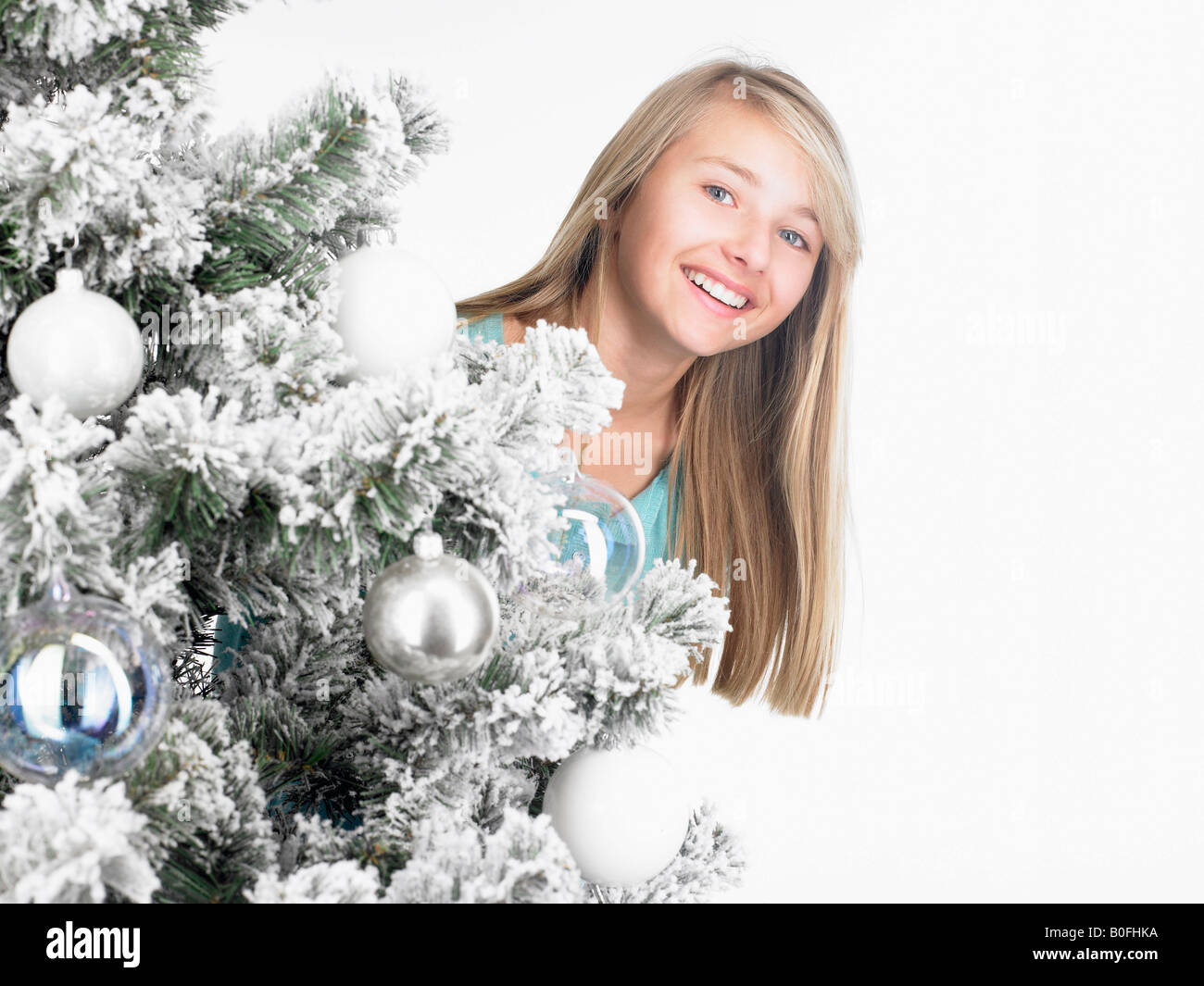 girl standing behind a fir-tree, smiling Stock Photo - Alamy