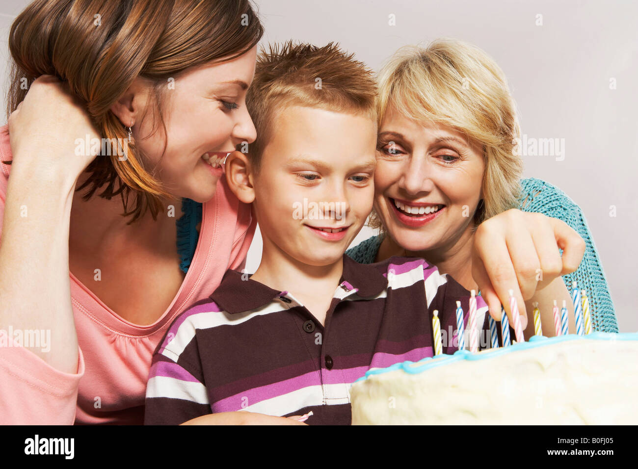 Grandmother, boy and mom decorating cake Stock Photo