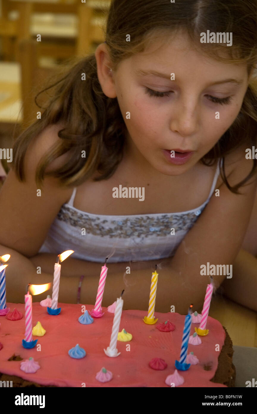Young girl blowing out her candles on her birthday cake (aged 8 Stock