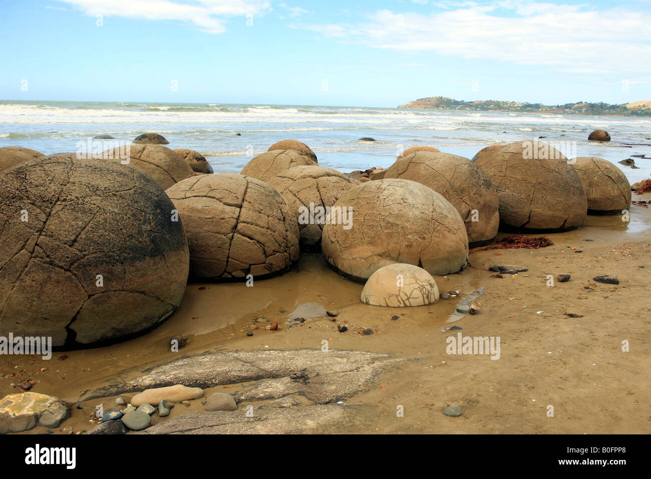 A giant ball shaped boulder almost covered in sand on the beach at Moeraki  South Island New Zealand Stock Photo - Alamy