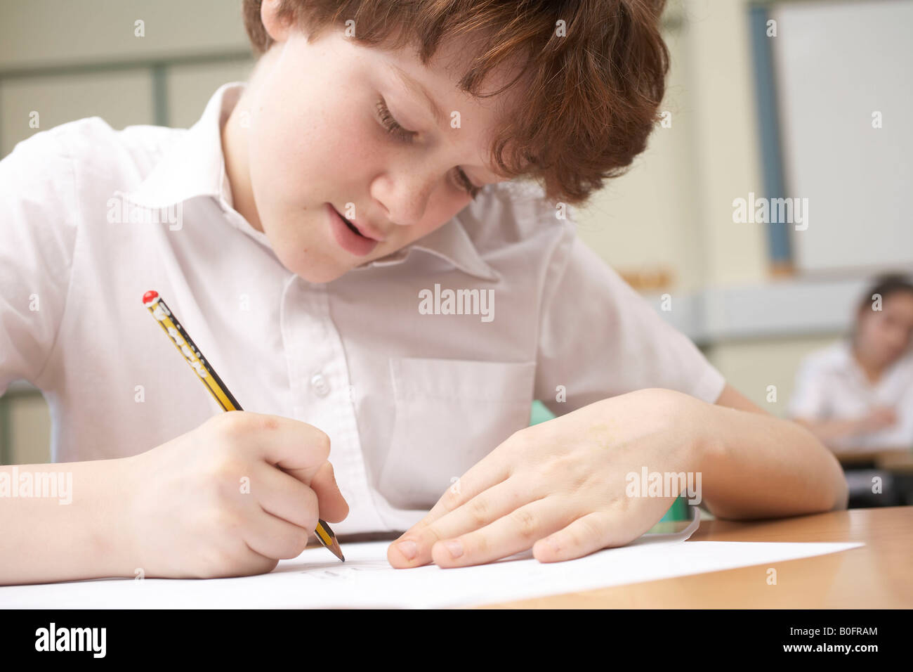 Boy writing in classroom Stock Photo