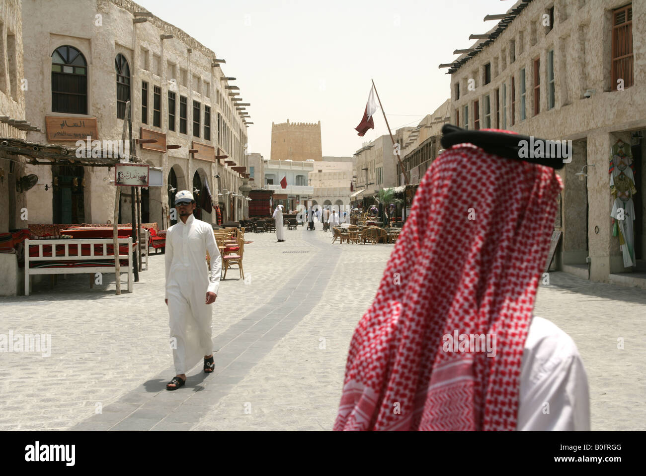 Men in traditional attire strolling through the Souq Waqif market in Doha, Qatar. Stock Photo