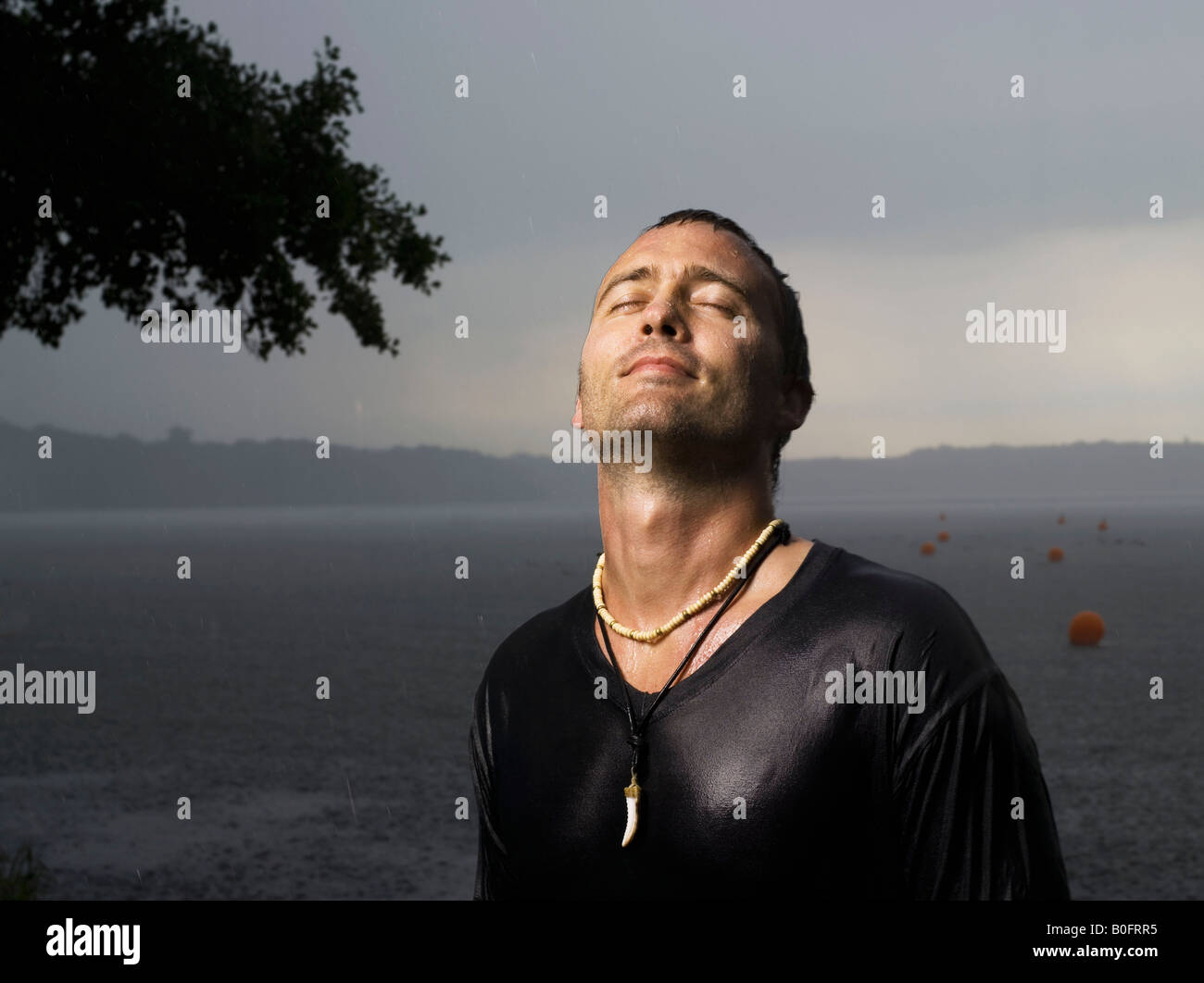 Man standing in rain, eyes closed Stock Photo