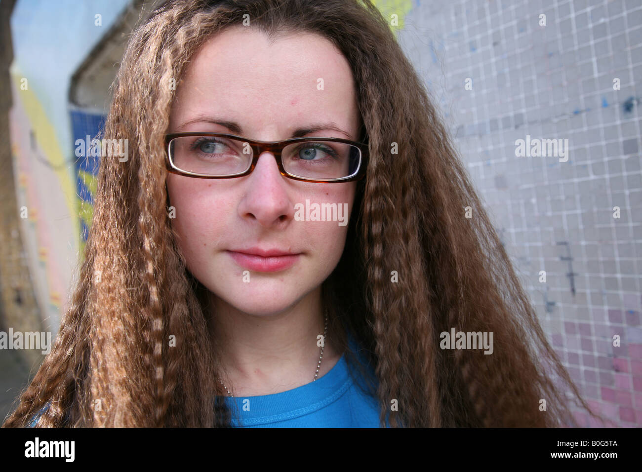 Caucasian female teenager / student looking depressed taken outside in a graffiti covered underpass on a council estate Stock Photo