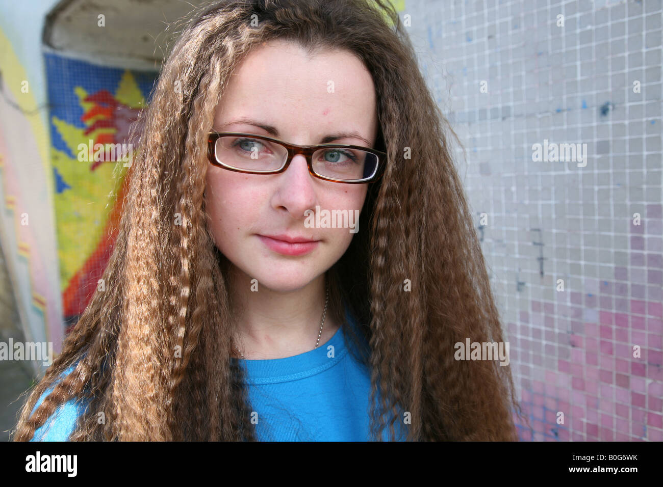 Caucasian female teenage student looking for trouble taken outside in a graffiti covered underpass on a council estate Stock Photo