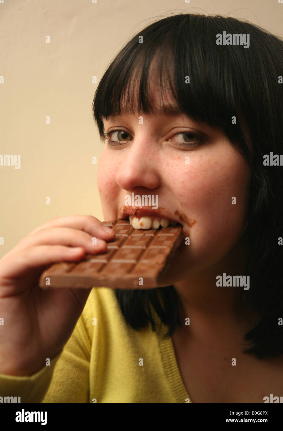 Teenage girl binge eating a large chocolate bar Stock Photo