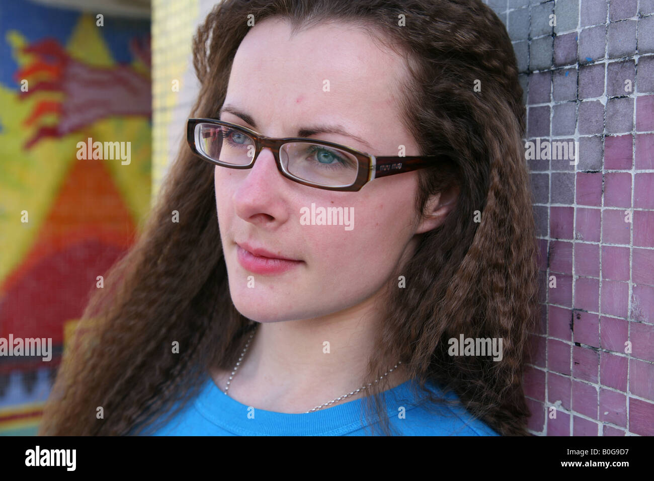 Caucasian female teenage student looking upset taken outside in a graffiti covered underpass on a council estate Stock Photo