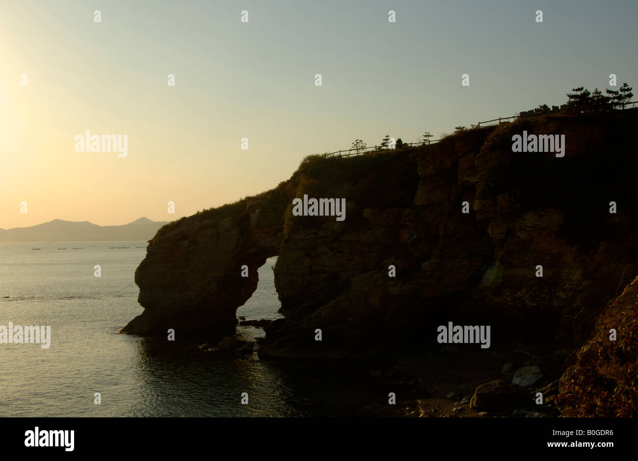 Eroded rocky coastline at Dalian Liaoning China depicts Dinosaur swallowing the Sea Stock Photo