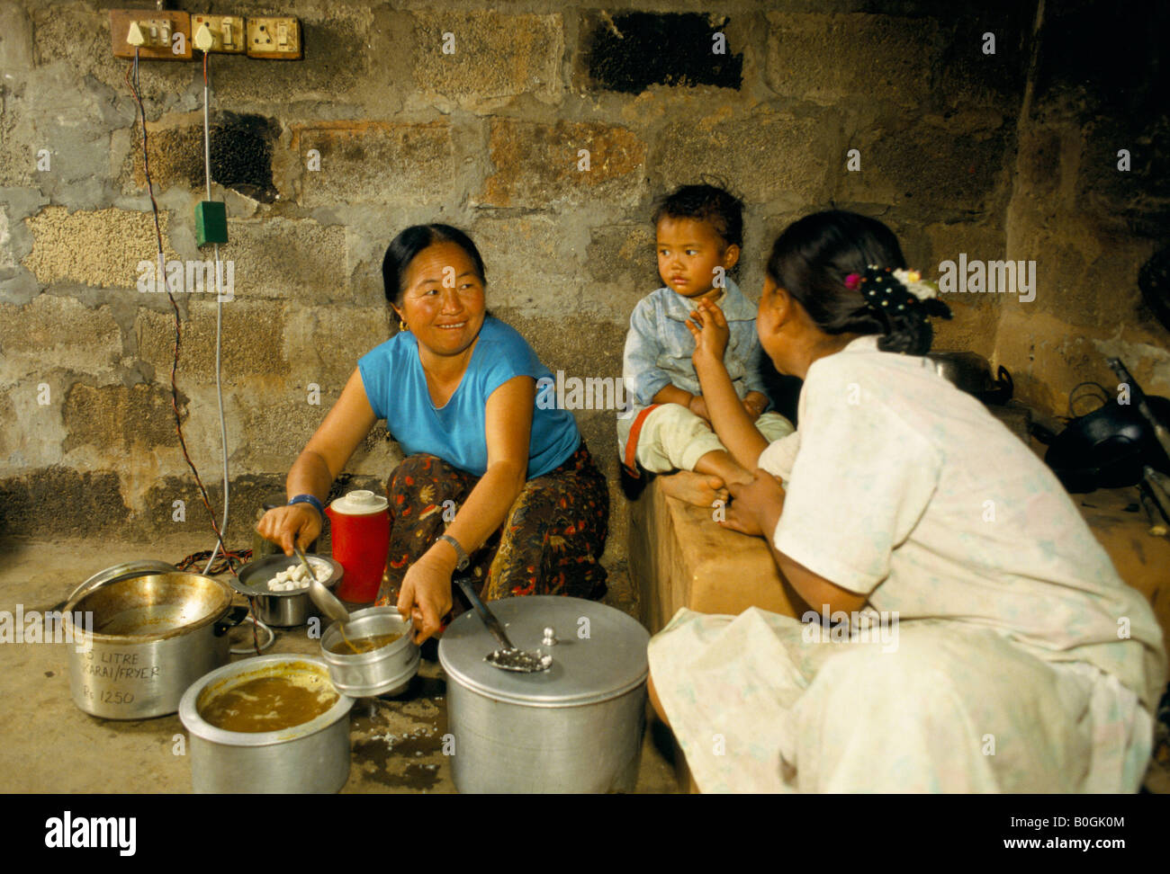 Women cooking dahl baht with a low-watt cooker in their kitchen, Galyang, Nepal. Stock Photo
