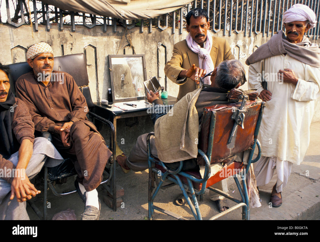 A street barber cutting a man's hair, with waiting customers, Karachi, Pakistan Stock Photo Alamy