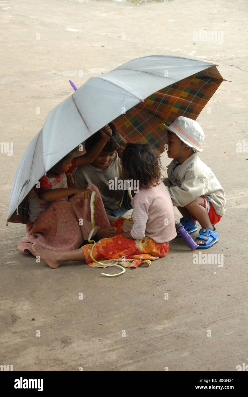 khmer children are enjoying themself by playing under the same umbrella