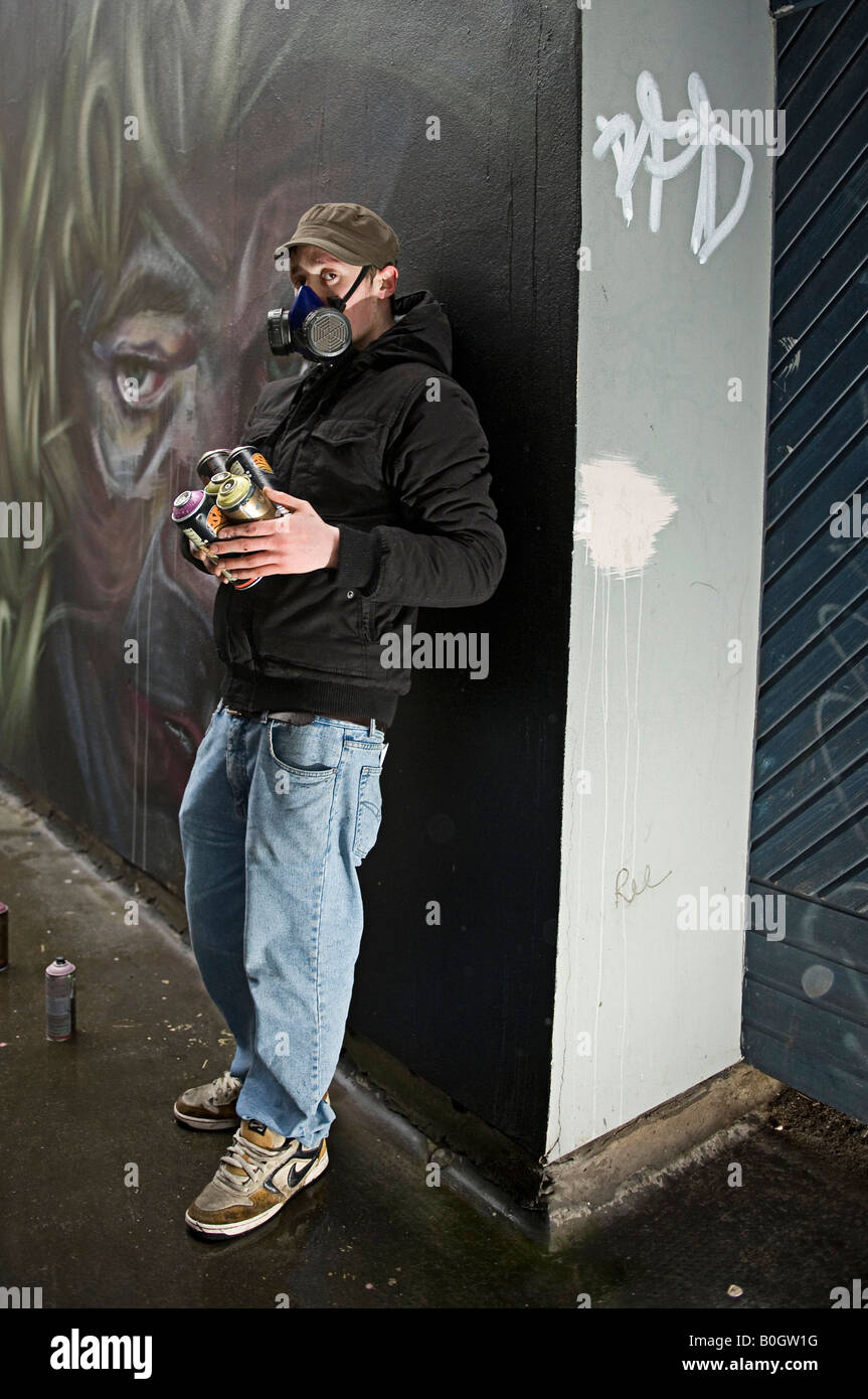 Graffiti Artist With Mask Spray Paints A Mural On A Wall Stock Photo Alamy