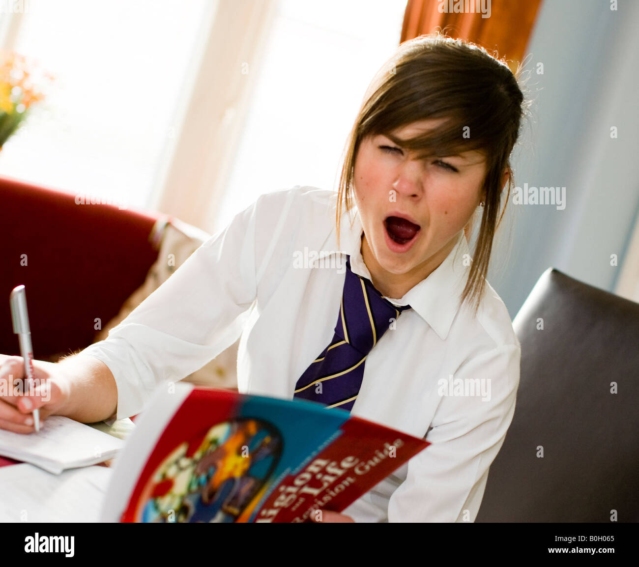 girl yawning as she does her revision Stock Photo