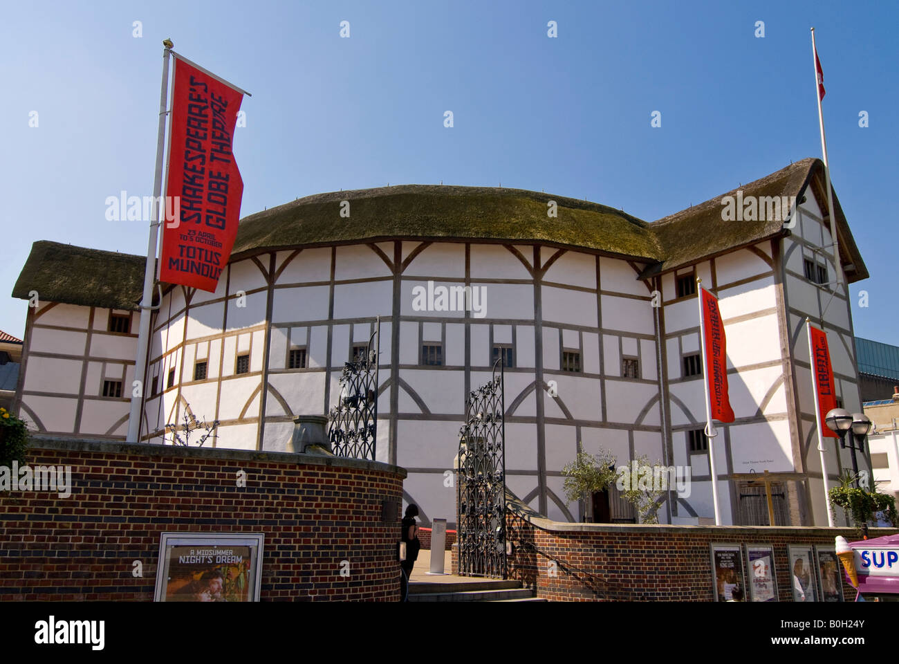 Horizontal wide angle of the front of Shakespeare's Globe Theatre against a bright blue sky. Stock Photo