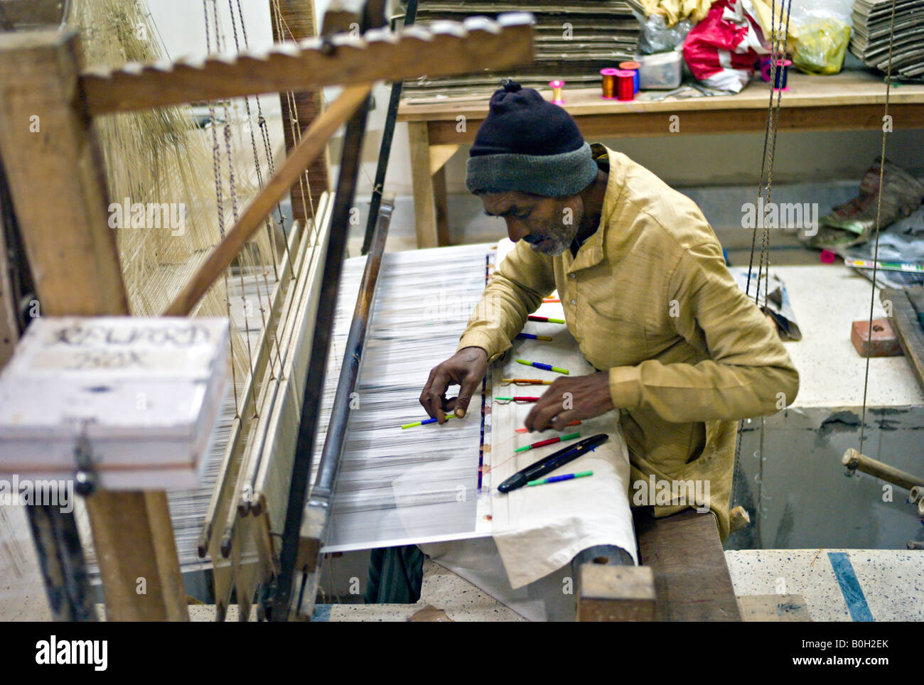 INDIA VARANASI Elderly Muslim man using a large loom to weave cloth in a factory in Varanasi famous for silk brocade Stock Photo
