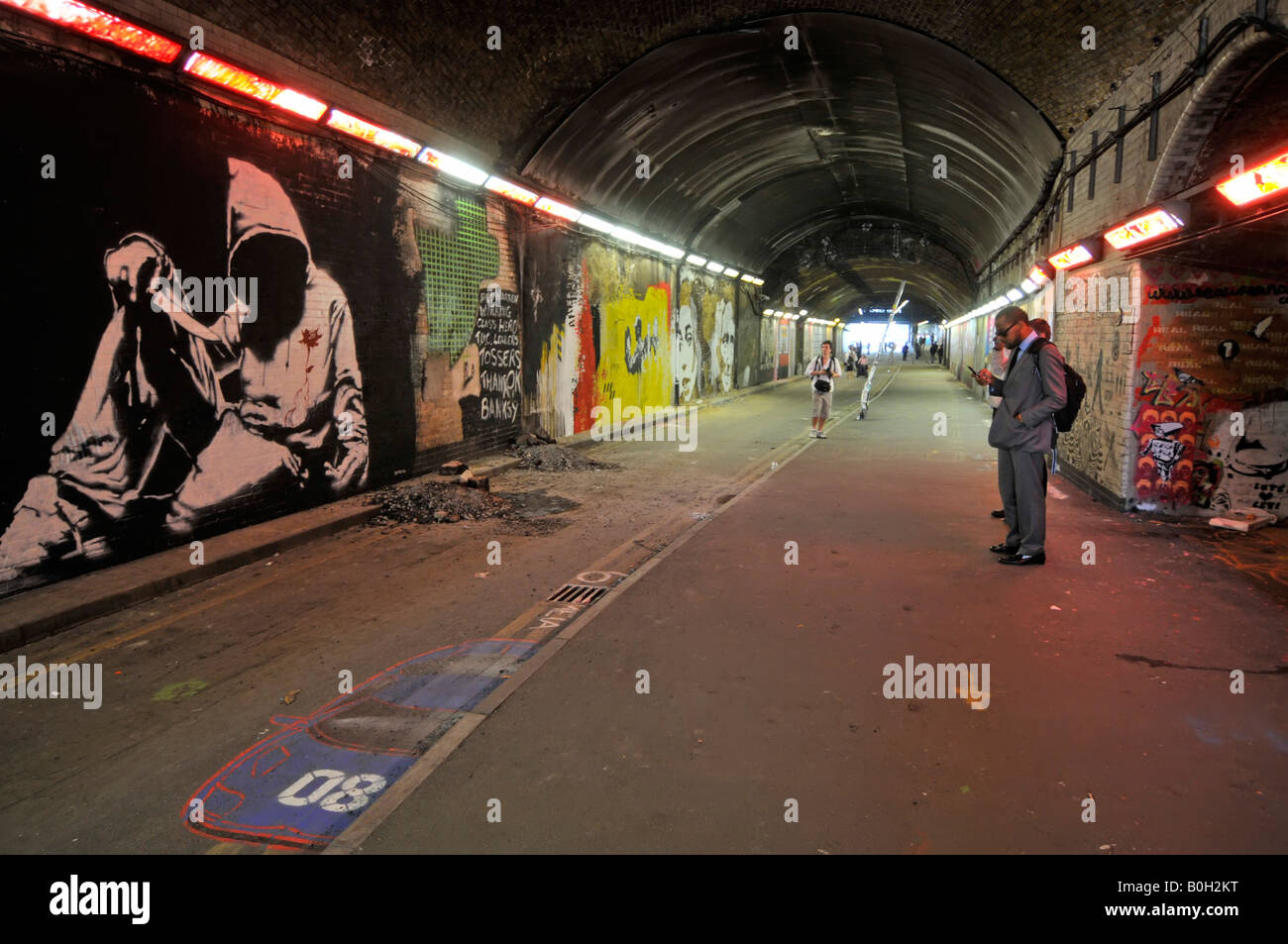 People stop to photograph Graffiti on walls of Leake Street London closed road tunnel under Waterloo train station & railway lines England UK Stock Photo
