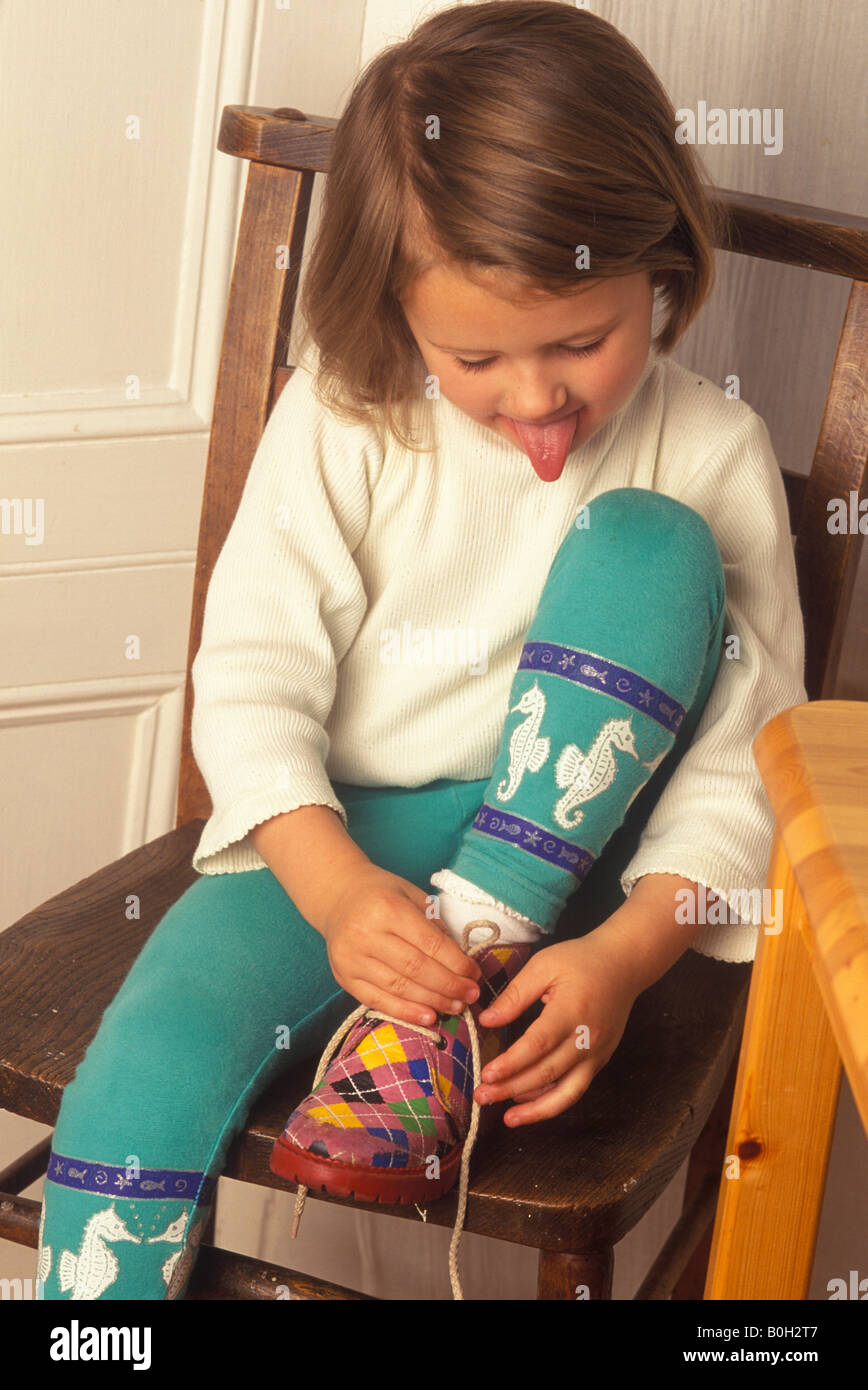 little girl tying her laces with concentration Stock Photo