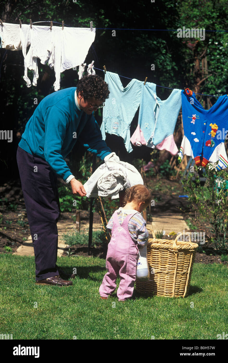 toddler helping father to hang out washing Stock Photo