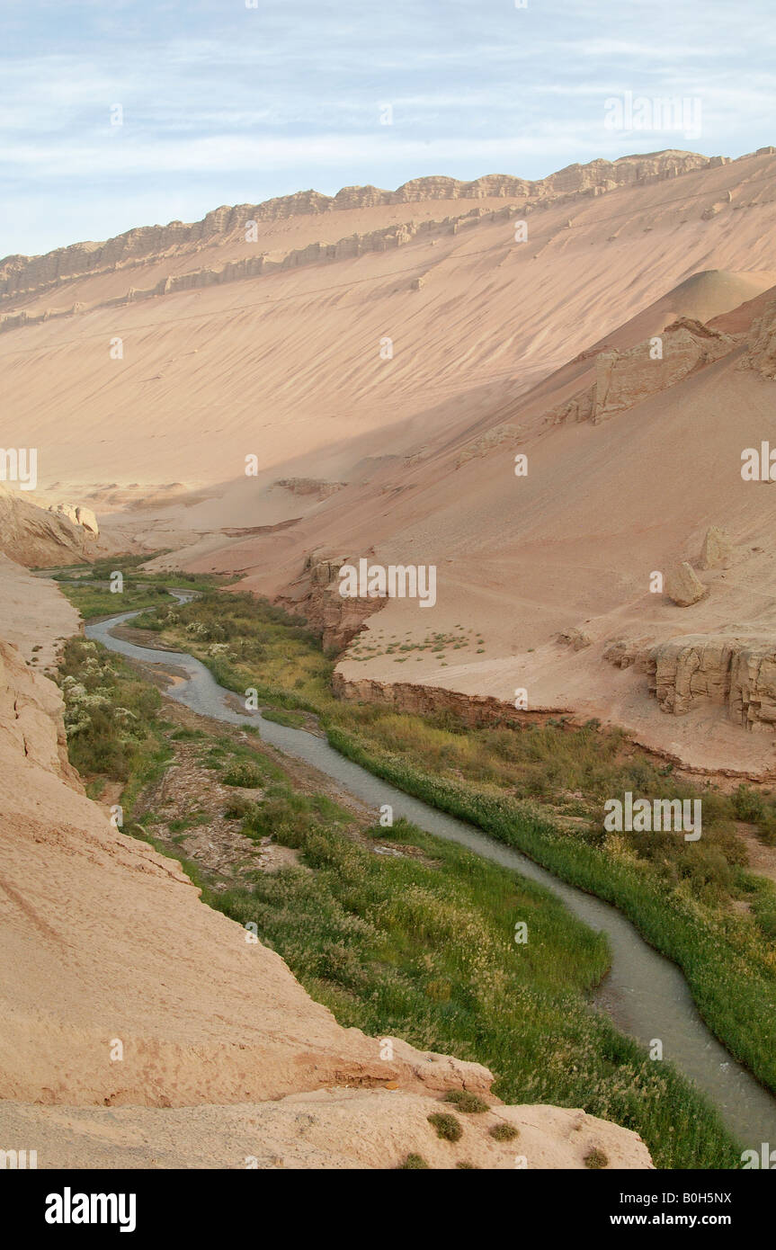 Fertile Murtuk river flows through heart of desert in gorge through Flaming Mountains Xinjiang Province China Stock Photo