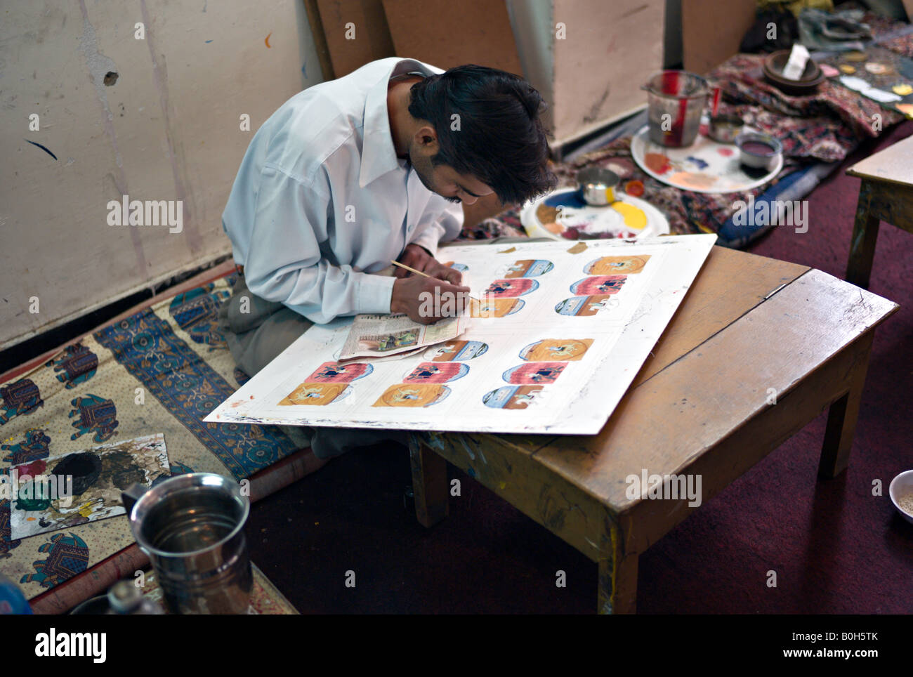 INDIA UDAIPUR Artist in a cooperative art studio painting miniatures Stock Photo